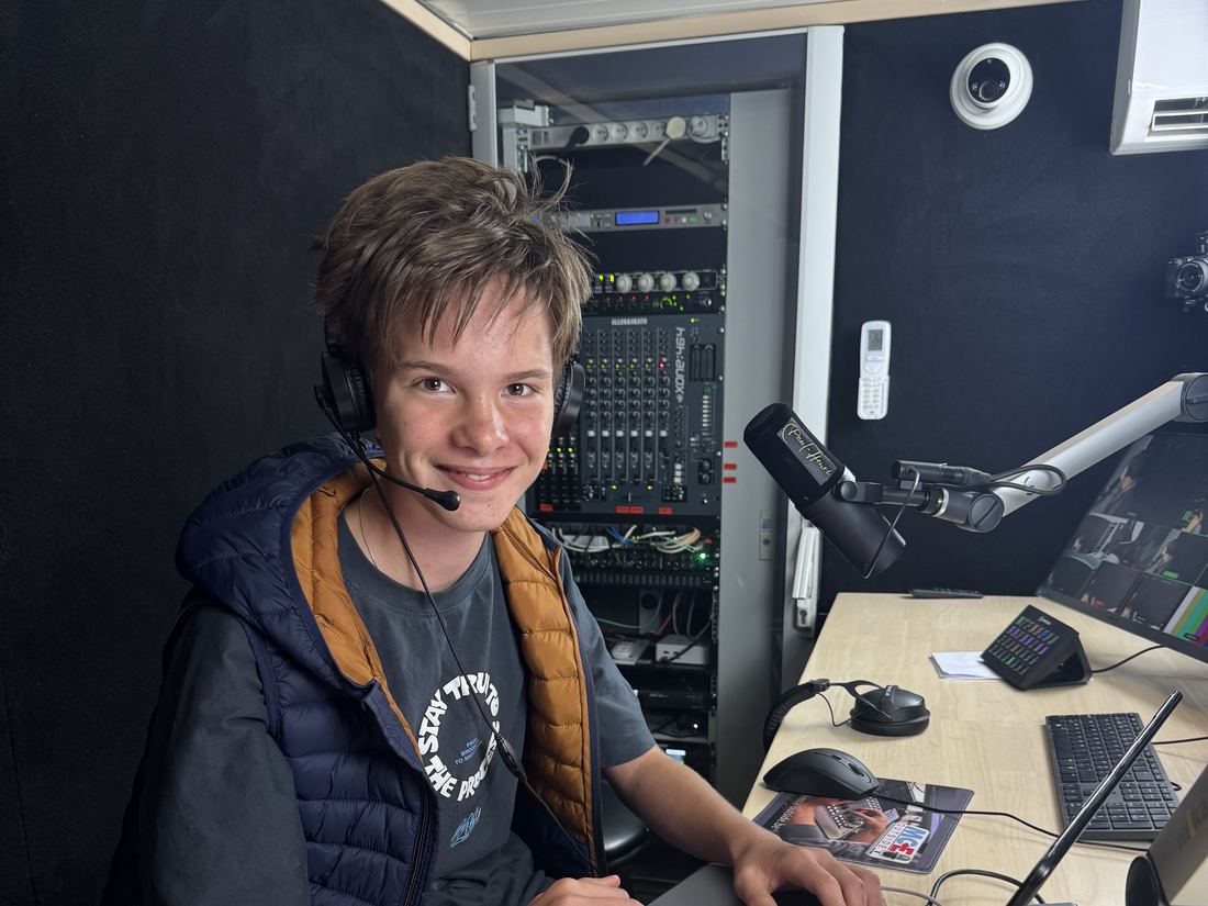 Emile-Henri met koptelefoon aan de micro in de podcaststudio